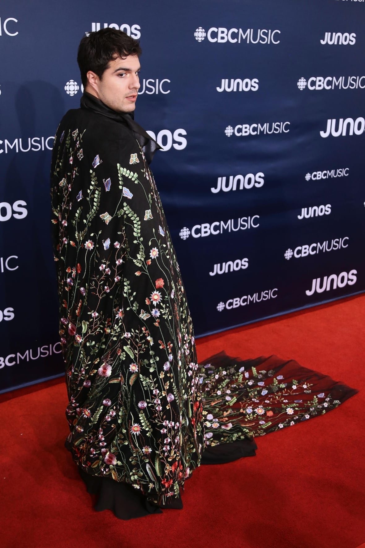 Jeremy Dutcher on the red carpet wearing a long, floral-embellished cape.