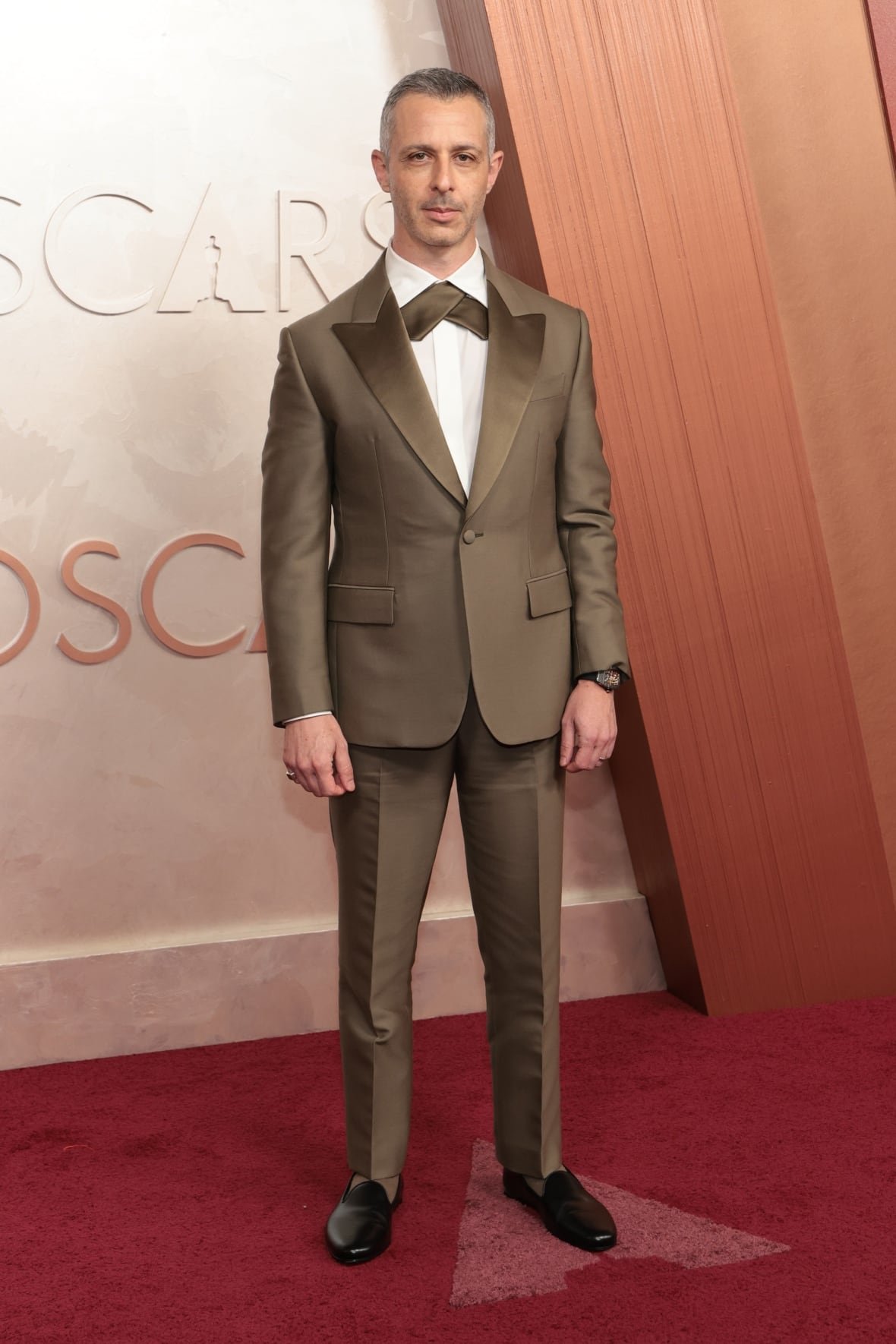 jeremy-strong-attends-the-97th-annual-oscars-at-dolby-theatre Jeremy Strong on the red carpet wearing an olive green tuxedo.