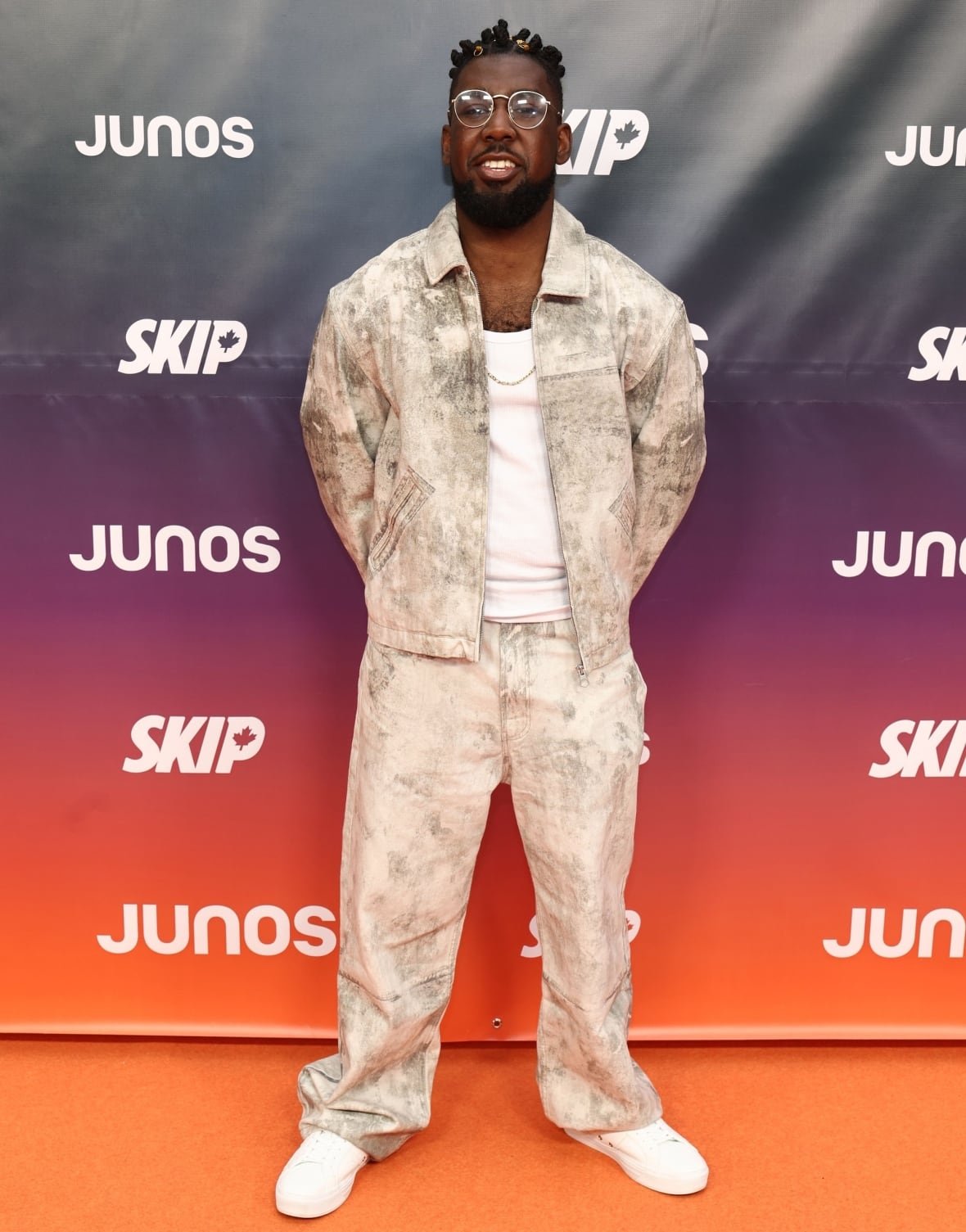King Cruff on the red carpet wearing a matching grey-and-white jacket and pants, white top and white sneakers.