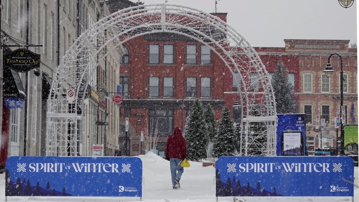 A person walks under an arch in a snowy downtown scene.