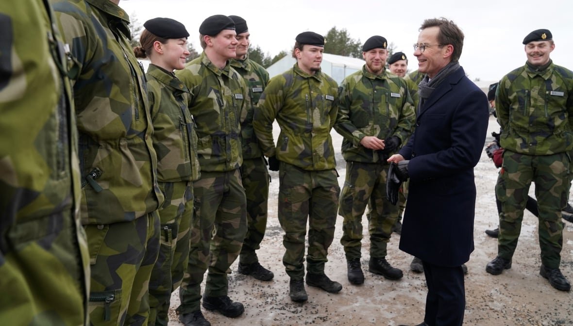 A man greets soldiers outdoors.