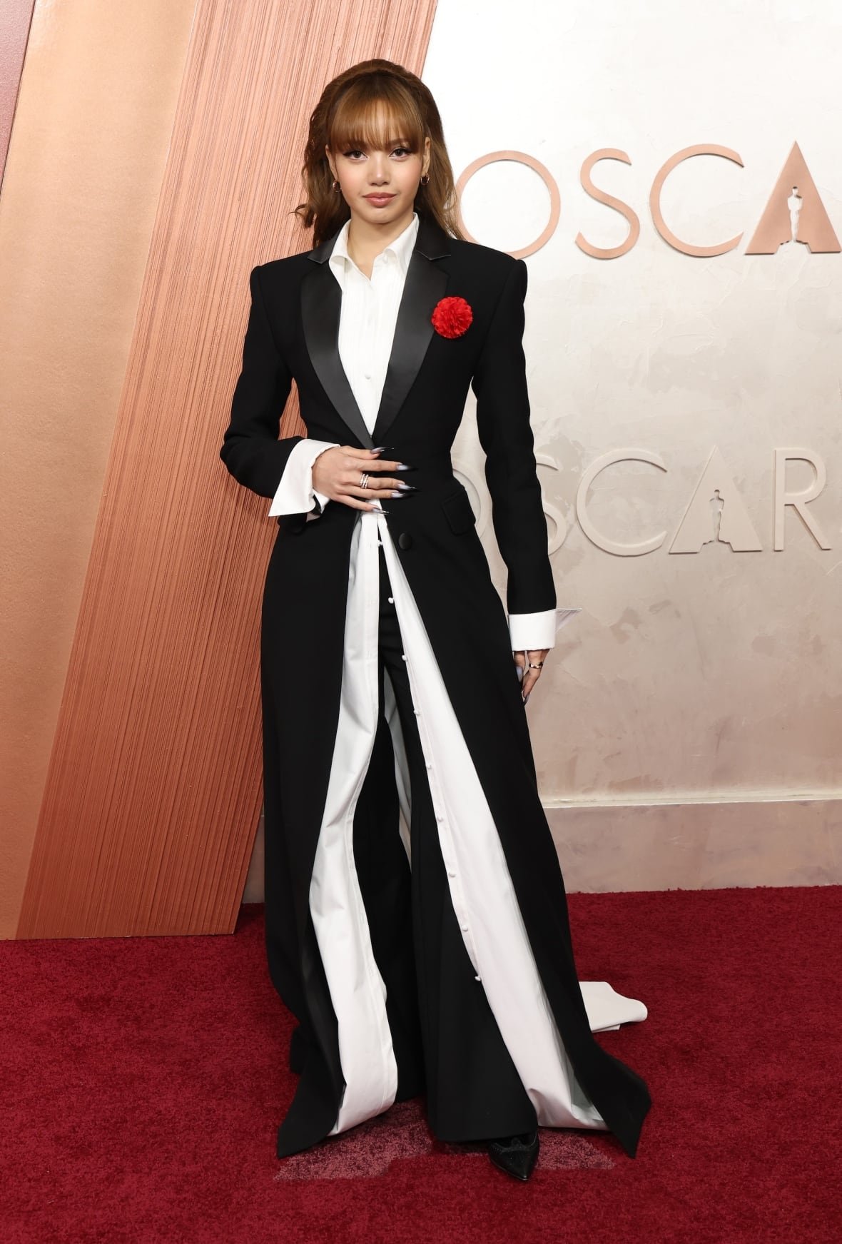 lisa-attends-the-97th-annual-oscars-at-dolby-theatre Lisa on the red carpet wearing a a floor-sweeping jacket layered over a white button-up shirt and black pants.