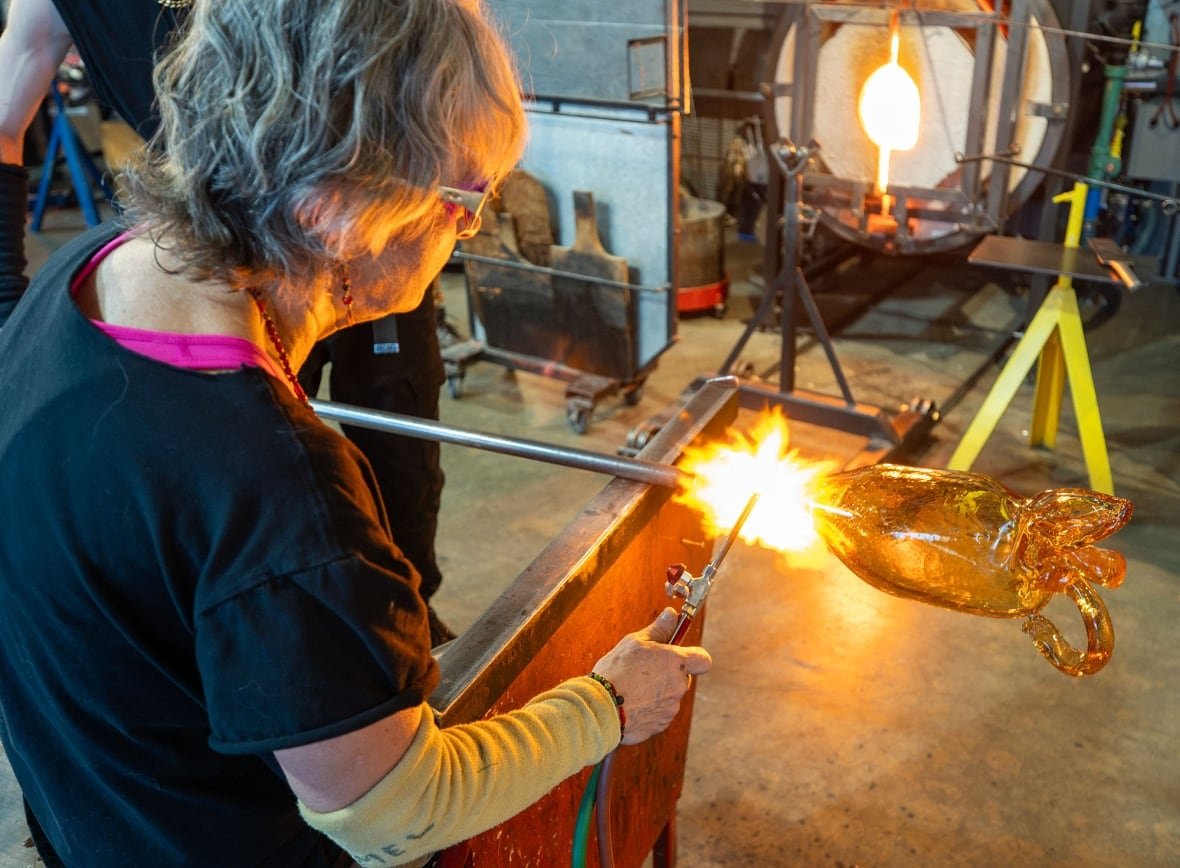 A woman works with glass and a torch.