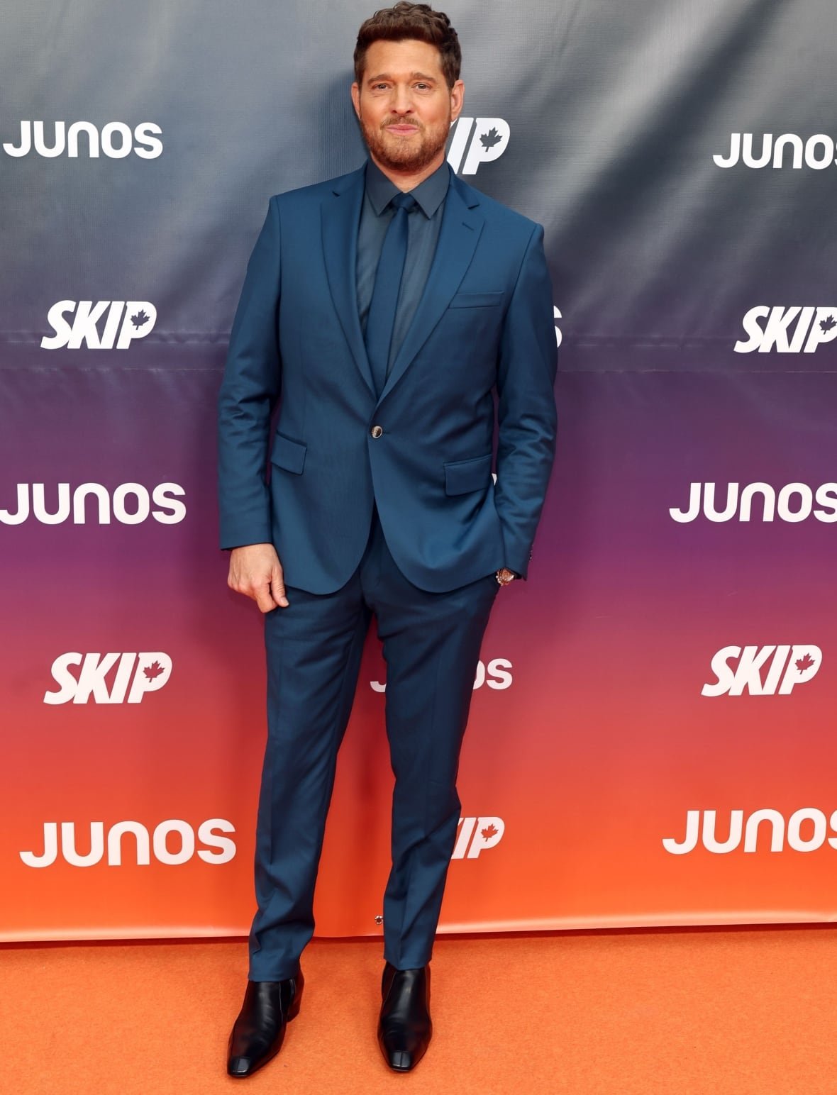 Michael Bublé on the Junos red carpet wearing a dark blue suit and black boots.