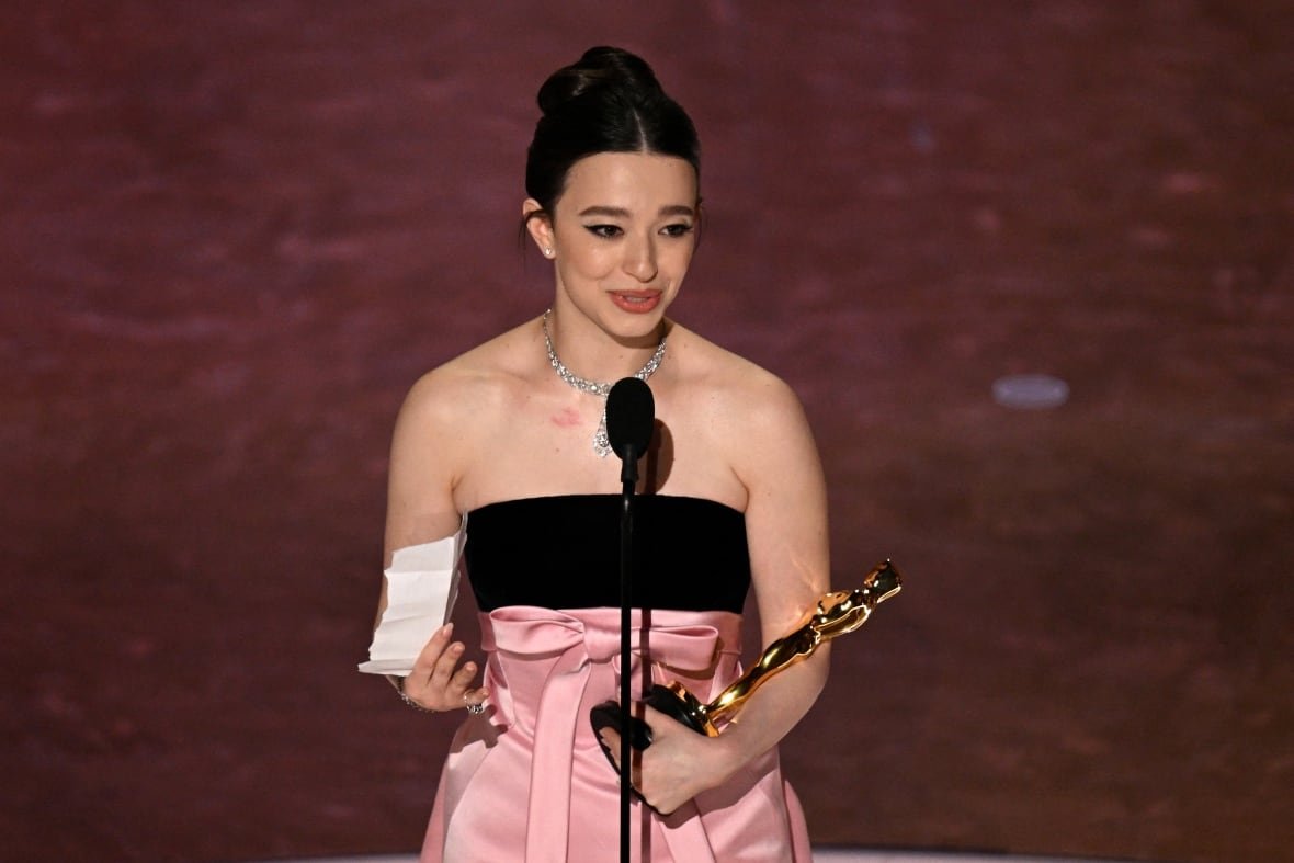 mike-madison A young woman in a pink and black dress holds a trophy.