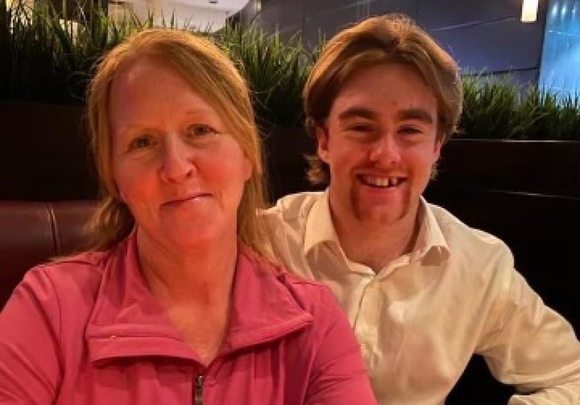 mooseheads-player-scores-memorable-goal-he-dedicated-to-his-late-mother-image-2 A woman wearing a pink sweater sits next to a man wearing a white sweater.