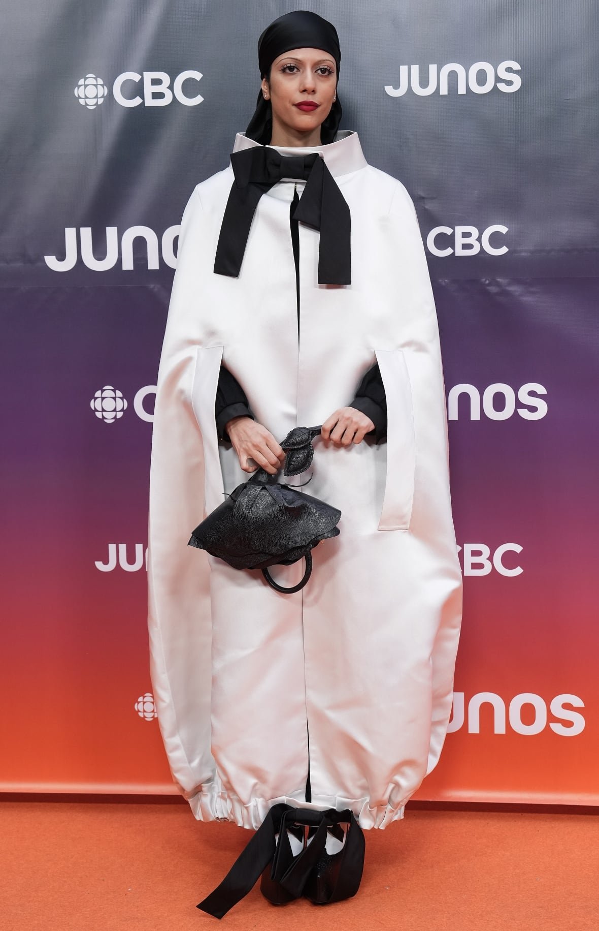 Nemahsis on the red carpet wearing a white satin cape coat.