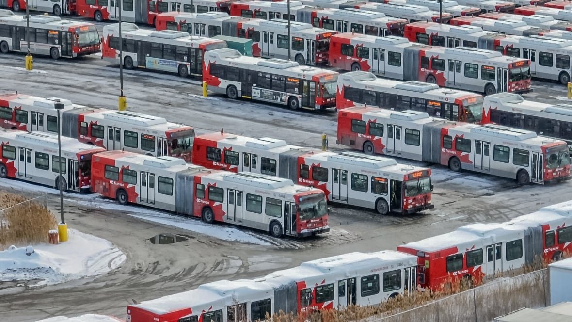 oc-transpo-bus-hq-drone-vis-ottawa A photo of dozens of public buses, all parked in a lot in rows.