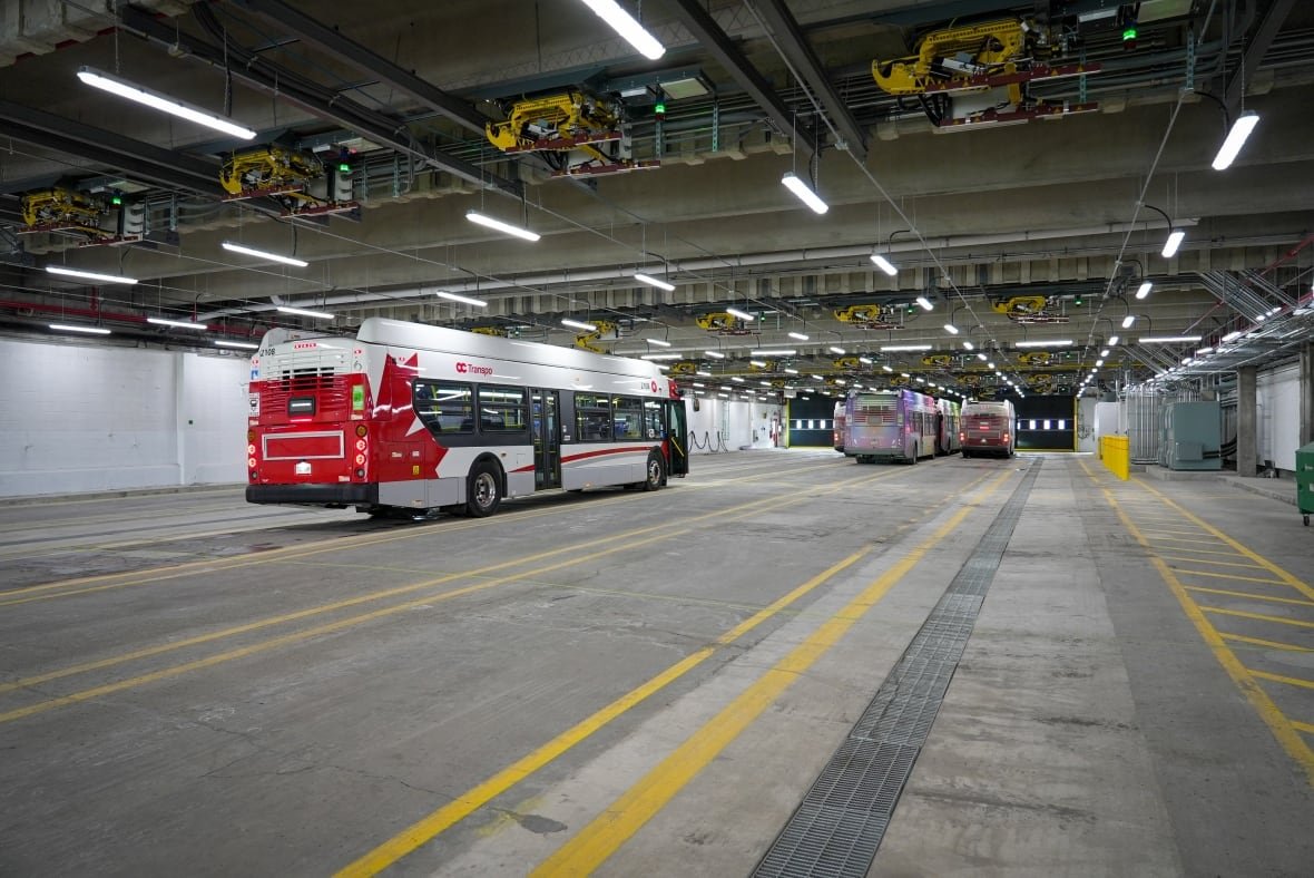 oc-transpo-st-laurent-bus-garage-bay-electric-buses-ebuses-jan-30-2025 A garage with yellow lines marking lanes and several parked buses