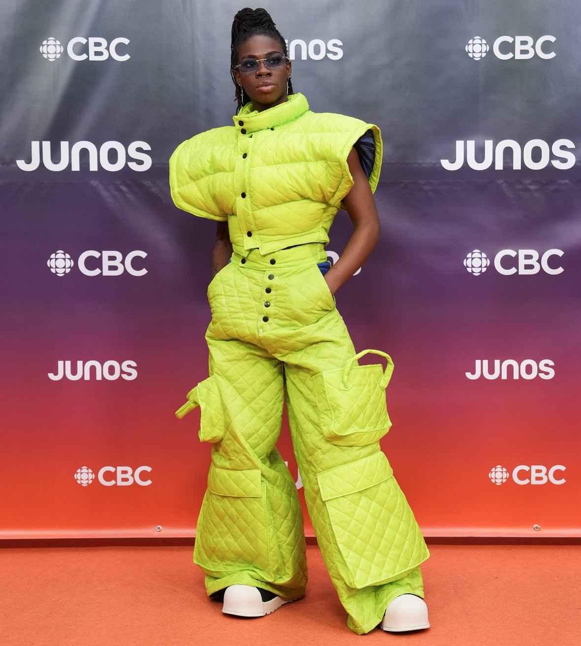 Omega Mighty on the red carpet wearing neon green puffer vest and pants.