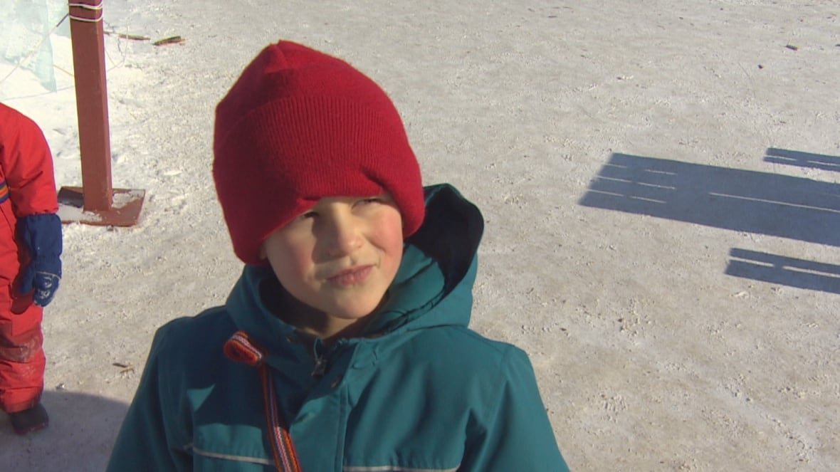 A child bundled up in winter gear looks ahead.