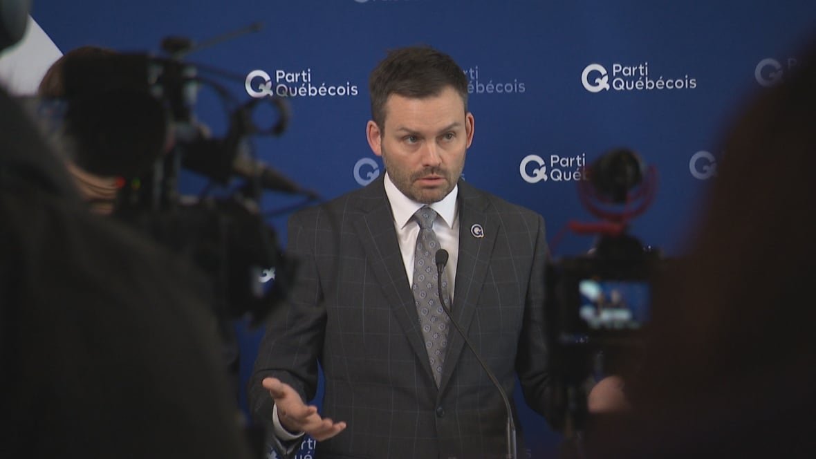The PQ leader stands before several news cameras and a podium.