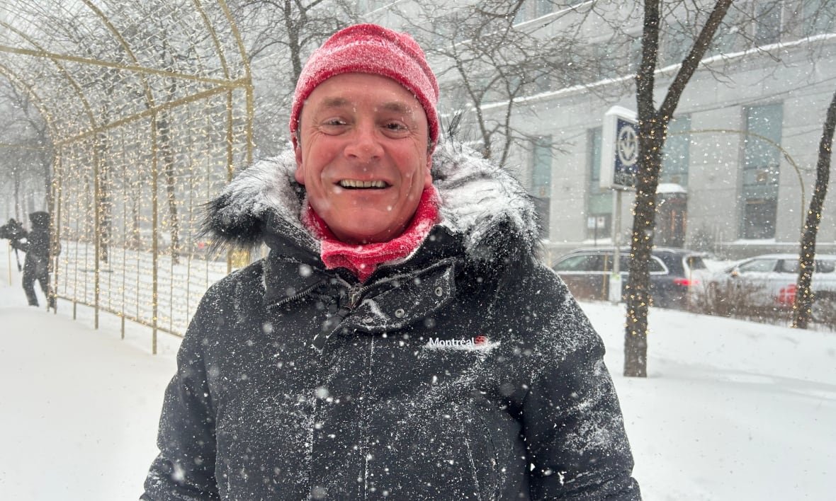 philippe-sabourin-under-blizzard A man covered in snow with a red hat and scarf. There's a blizzard going on.