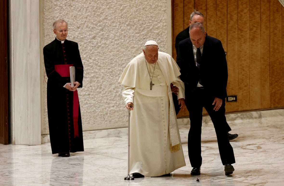 Pope Francis is assisted by his aide after a part of his cane broke off during his arrival to hold the Jubilee audience in Paul VI Hall at the Vatican on February 1, 2025.