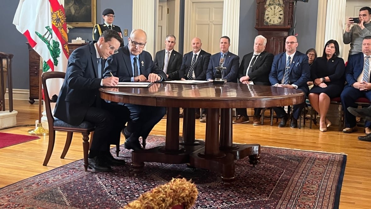 Rob Lantz, left, P.E.I.'s new premier, signs the paperwork to make it official during a swearing-in ceremony Friday at Fanningbank as Lt.-Gov. Wassim Salamoun looks on.
