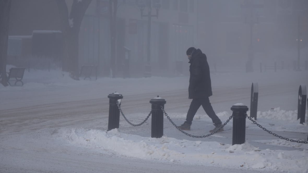 saskatoon-extreme-cold A person walks on a snow-covered sidewalk.