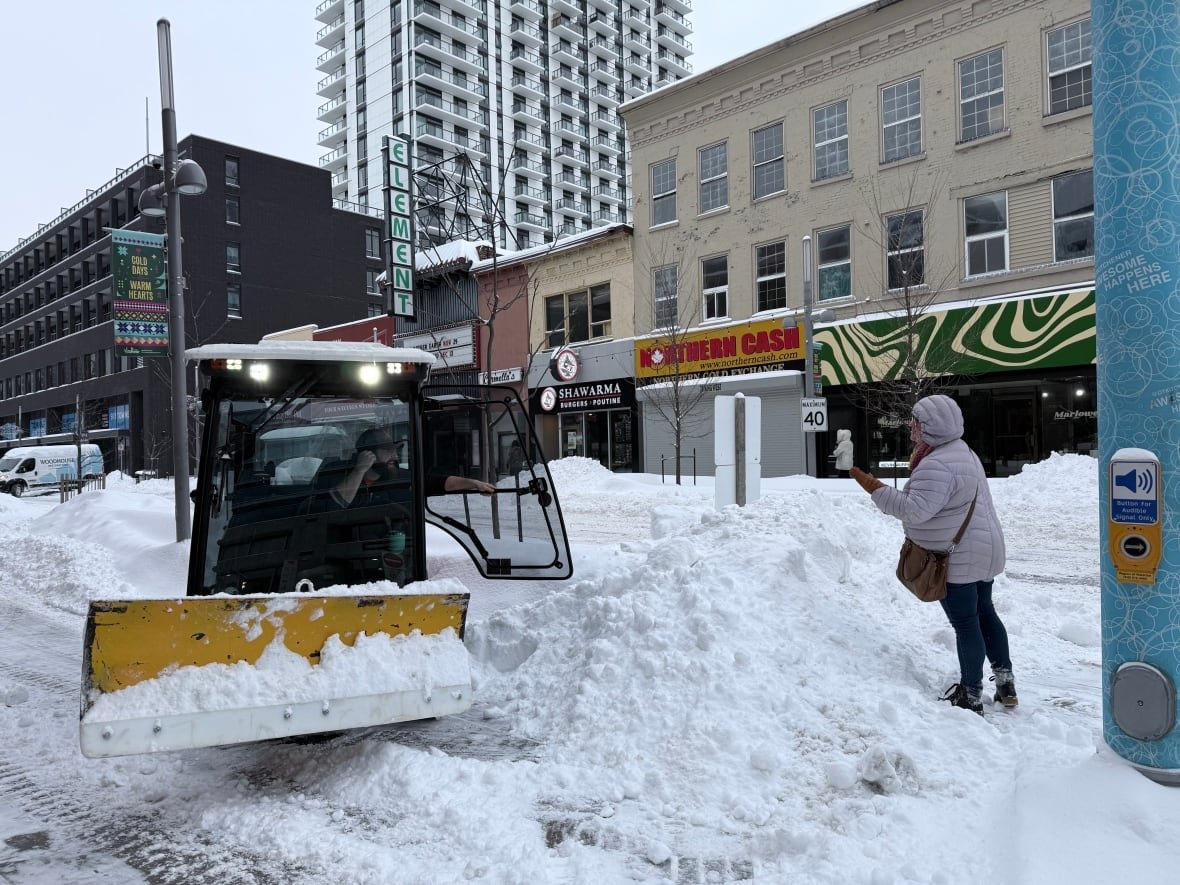 A snow plow driver talks to a woman.