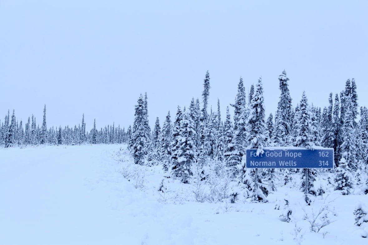 A sign covered in snow on a wintery landscape.