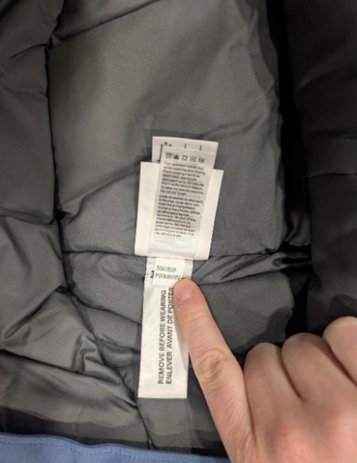 A person uses their finger to display a jacket's inner tag.