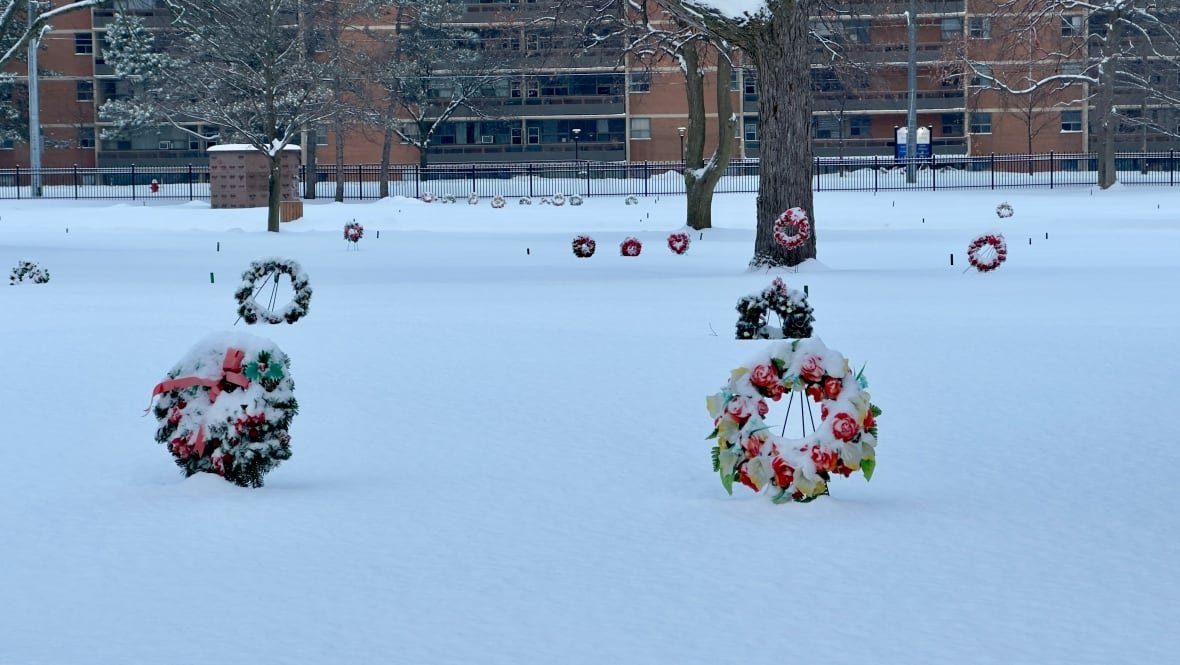 Wreaths in a cemetery peak out of the snow.