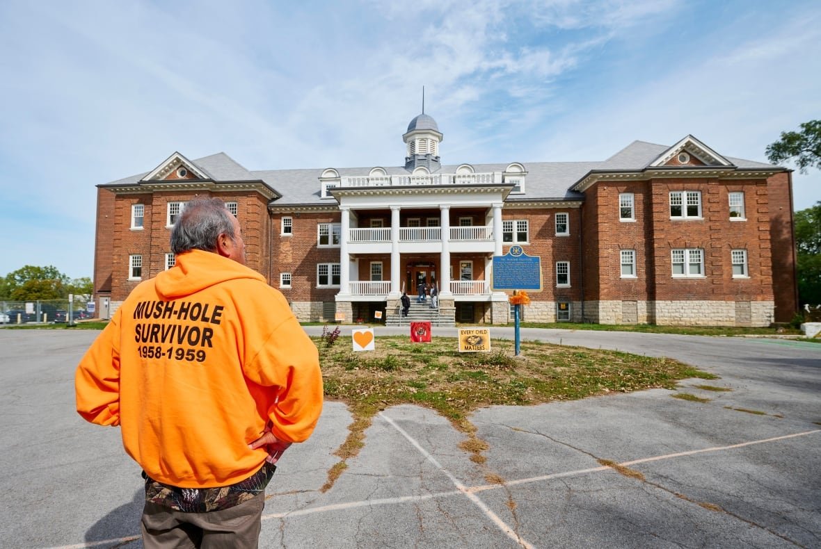 ss Residential school survivor stands in front of former Mohawk Institute.