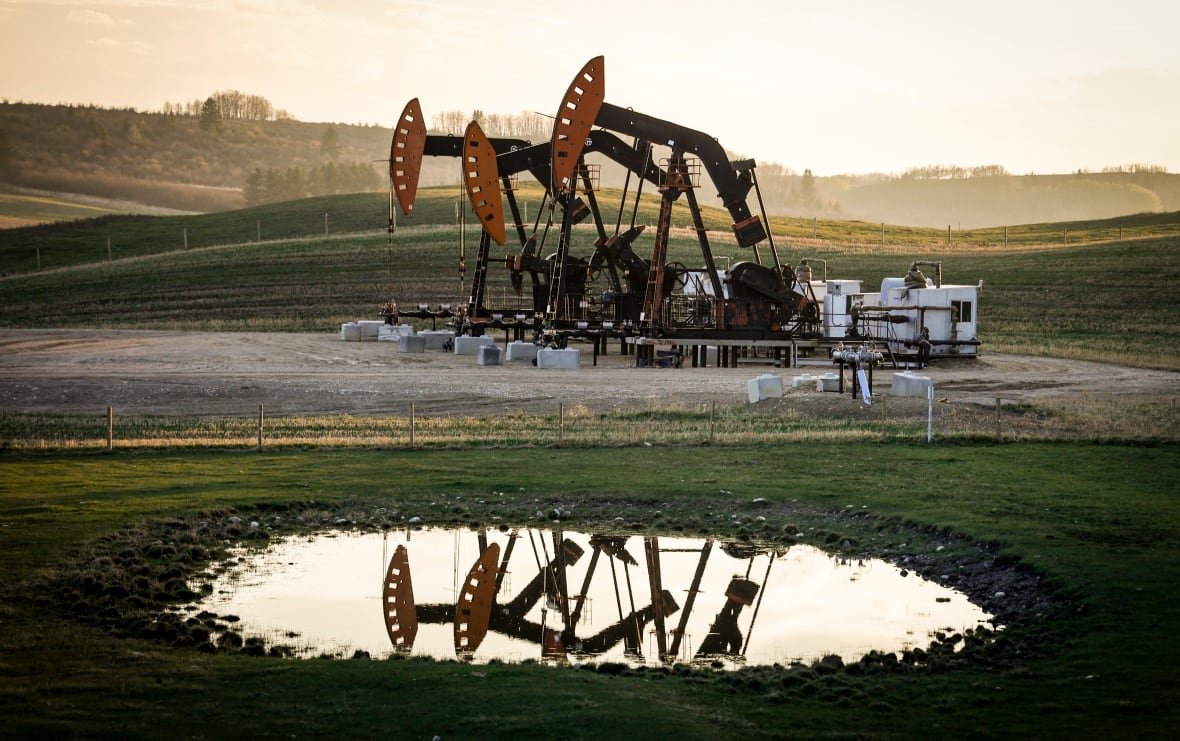 statcan-gdp-20240628-1 Pumpjacks are seen in front of a sunset.