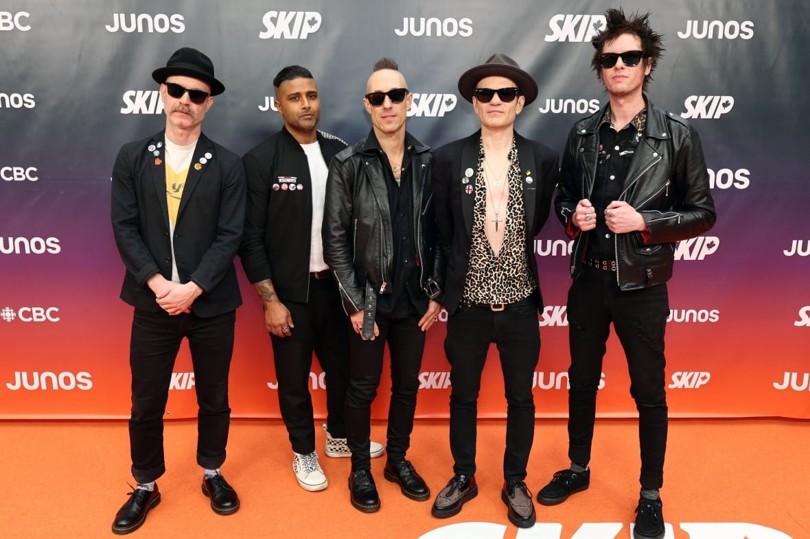5 men on the red carpet wearing black pants and black jackets.