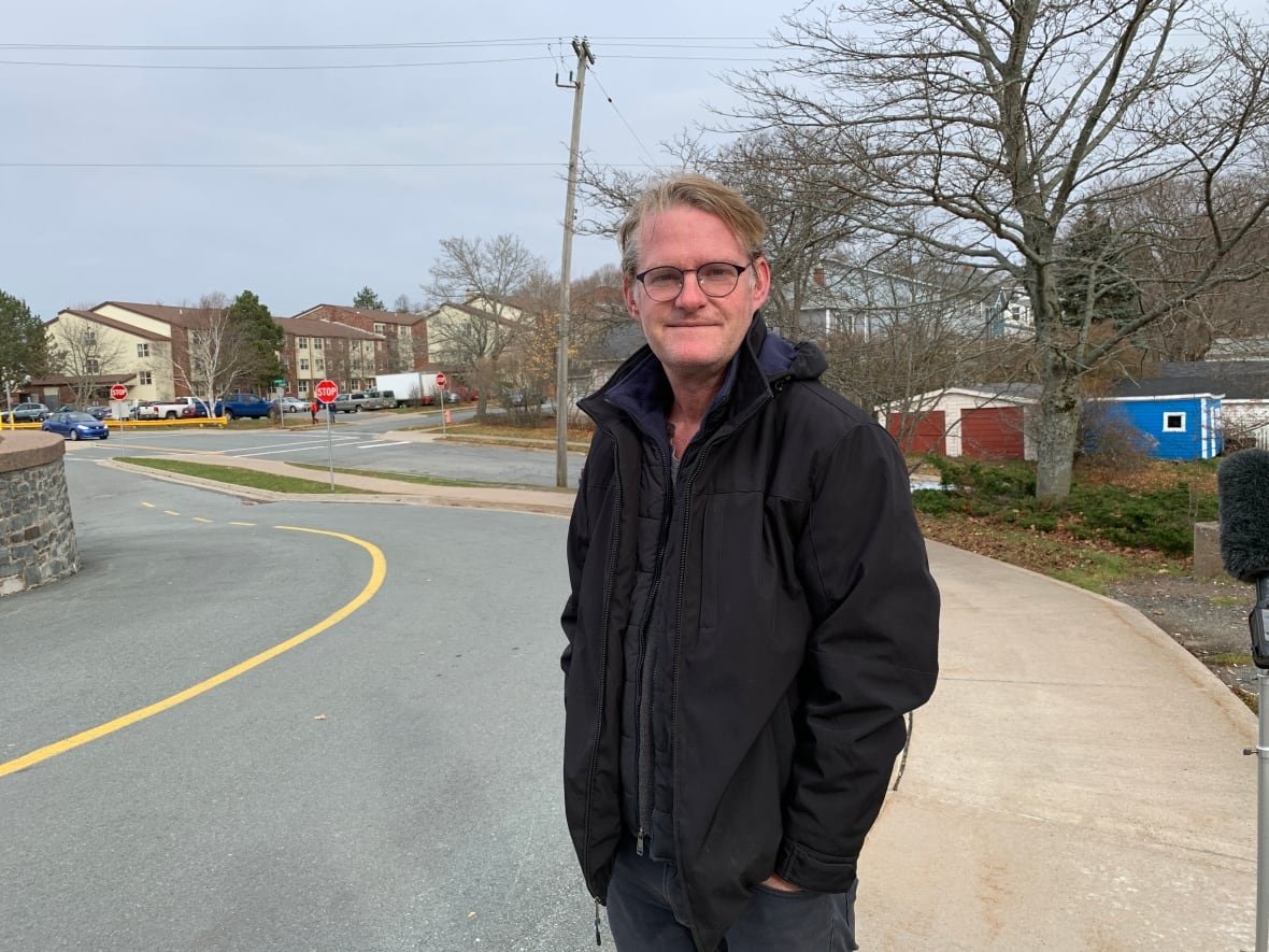 tod-augusta-scott A white man is seen standing on a sidewalk. He is wearing black glasses and a black jacket