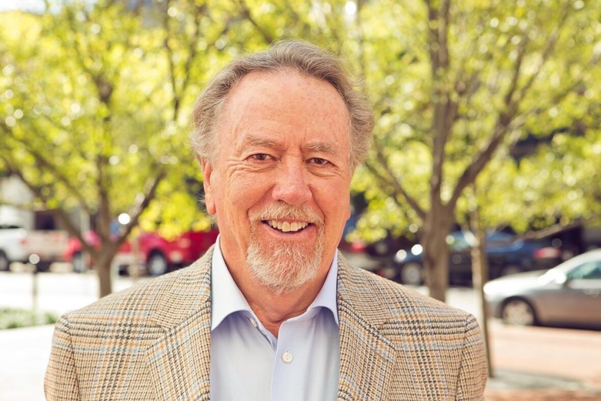A smiling man wearing a plaid blazer