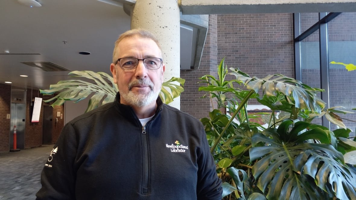 tourism-minister-steve-crocker Man in black sweater standing in front of green plant.