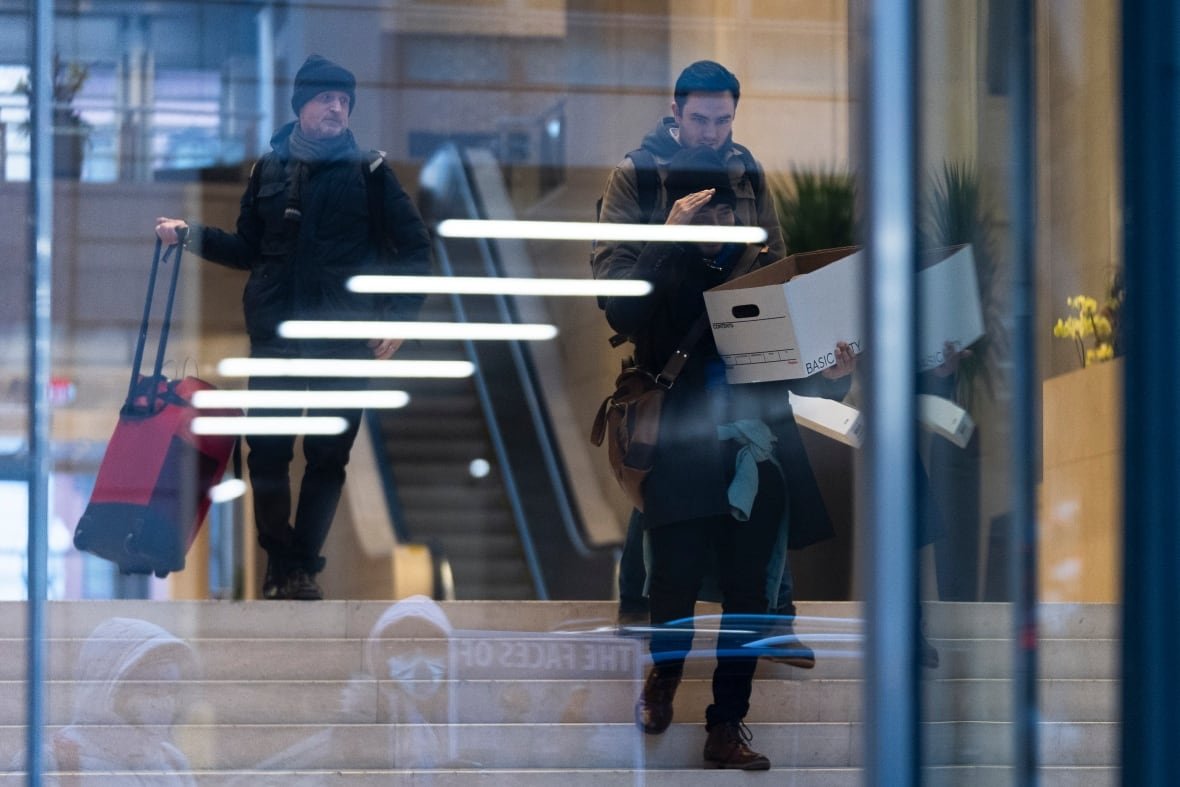trump-usaid-2 People are seen through a window carrying boxes as they descend a flight of stairs.