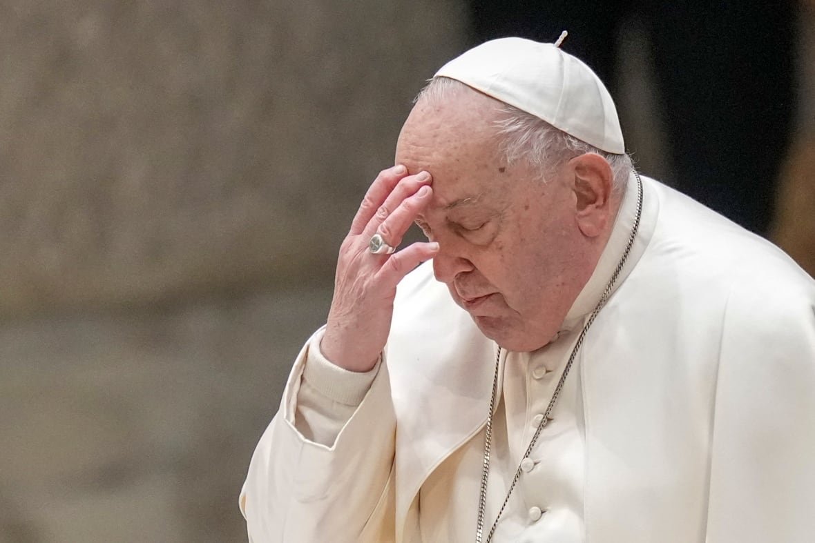 A person in religious garb touches their forehead with their fingers.
