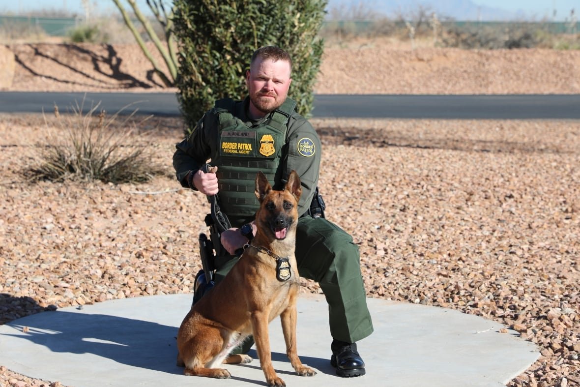 vermont-border-patrol-shooting A police officer kneels next to a dog while holding its leash.