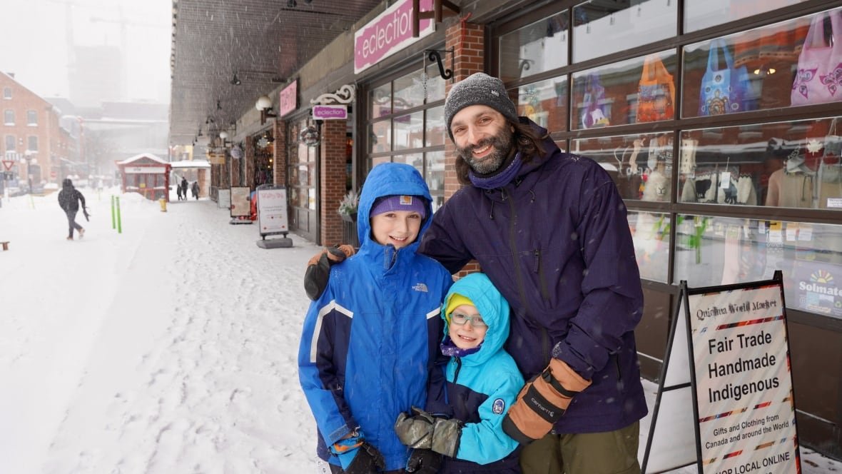 winterlude-burns-fam A man and two boys stand and smile in a snowy ByWard market.