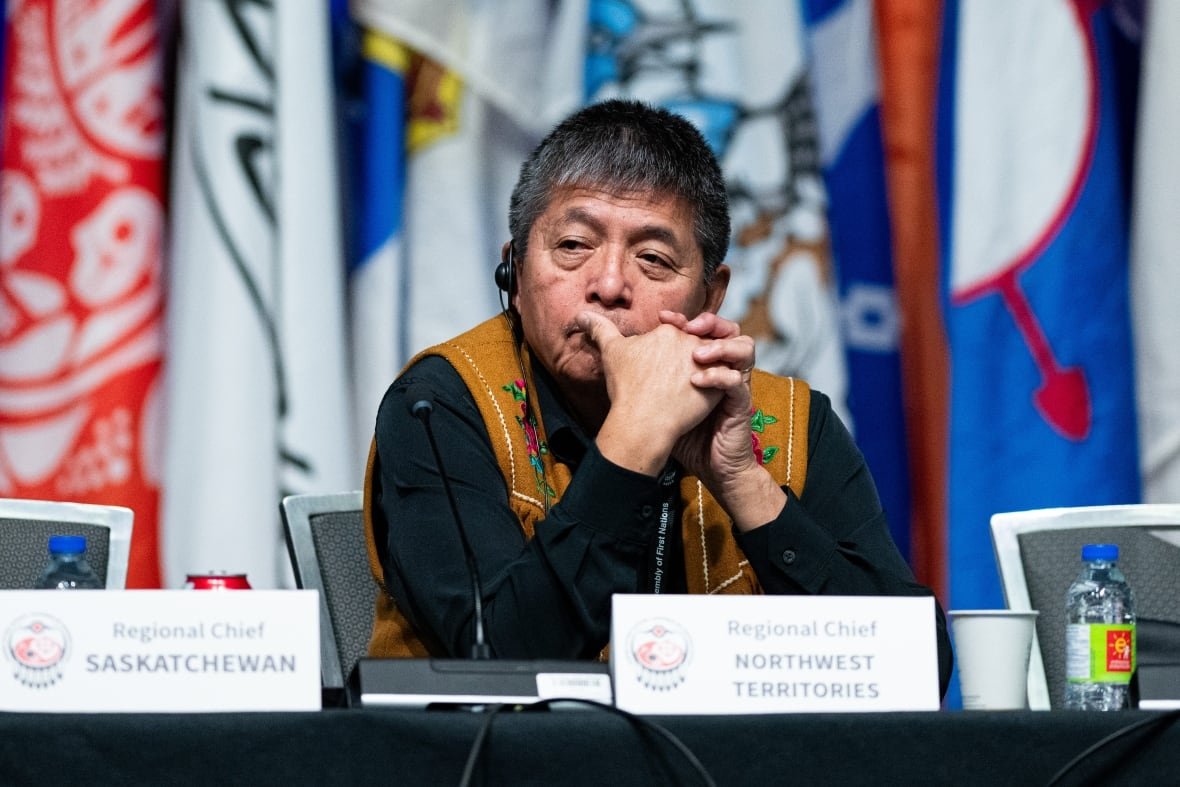 afn-assembly-20241204 A man sits pensively at a table, wearing a brown vest with flowers embroidered on it.