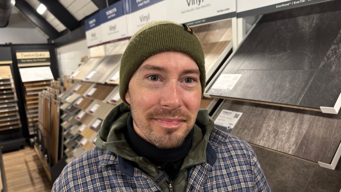 andrew-cameron Man standing in front of flooring tiles in a carpet and flooring business.