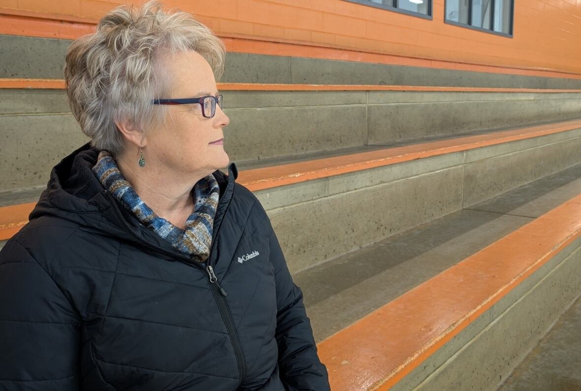 barbara-brookins A woman sits in the stands of a hockey rink. She is not looking at the camera.