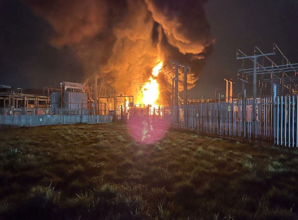 britain-heathrow-power-outage-1 Smoke and flames rise from a blaze at night at an electrical substation.