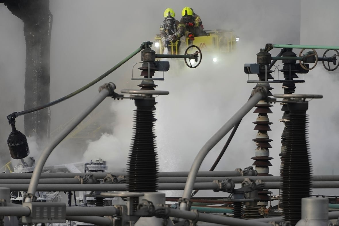britain-london-fire Two firefighters in helmet and uniform are shown atop the frame battling smoke at an industrial area.