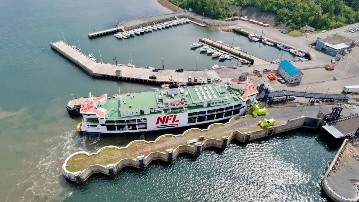 caribou-ferry-drone A drone view of a large blue and white ship docked at a port in summertime.