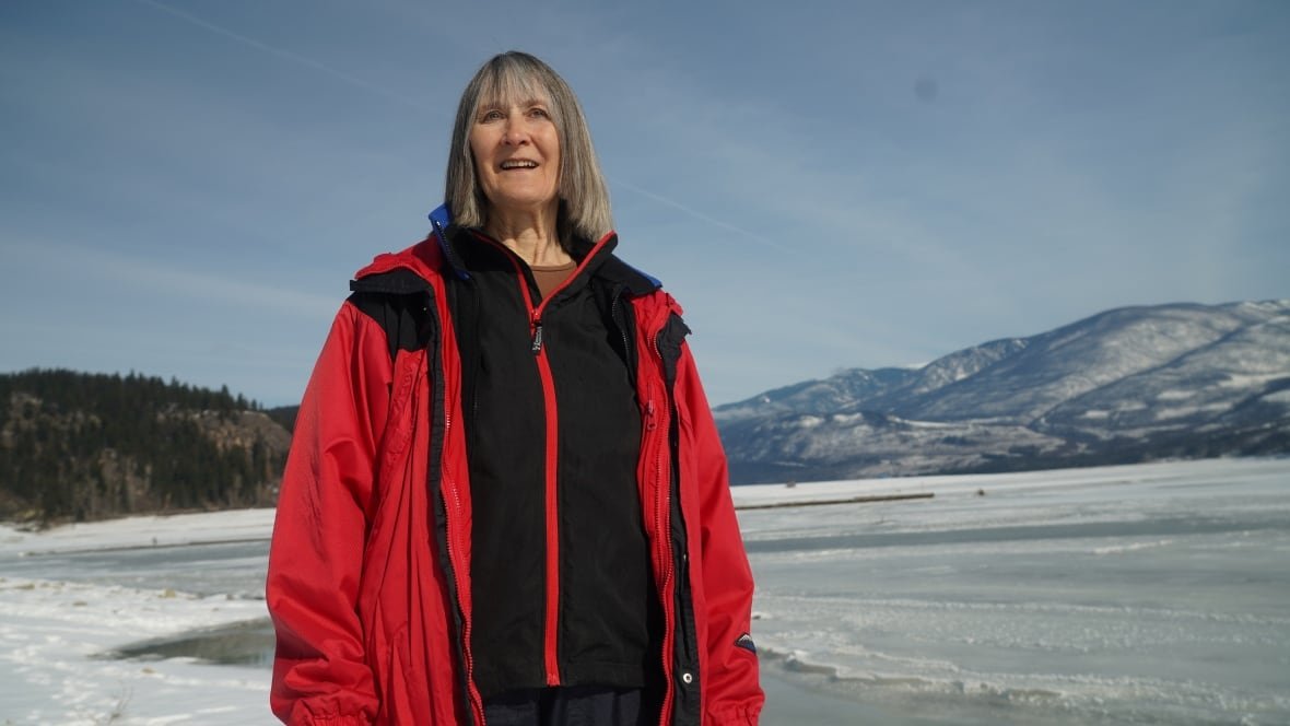 crystal-spicer-1 A woman with grey hair in a red snow coat stands by an icy reservoir near Edgewood B.C.