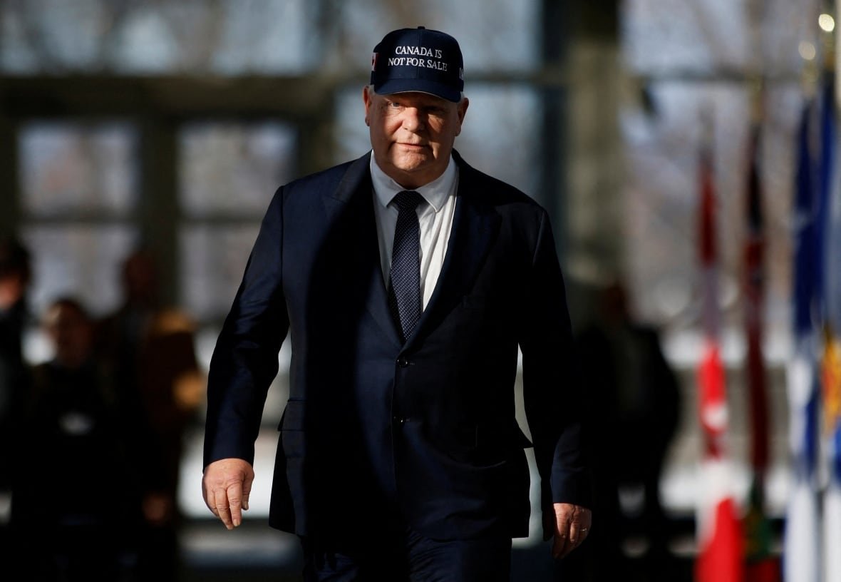 doug-ford-canada-hat-ottawa A politician wears a blue baseball hat as he walks to a news conference.