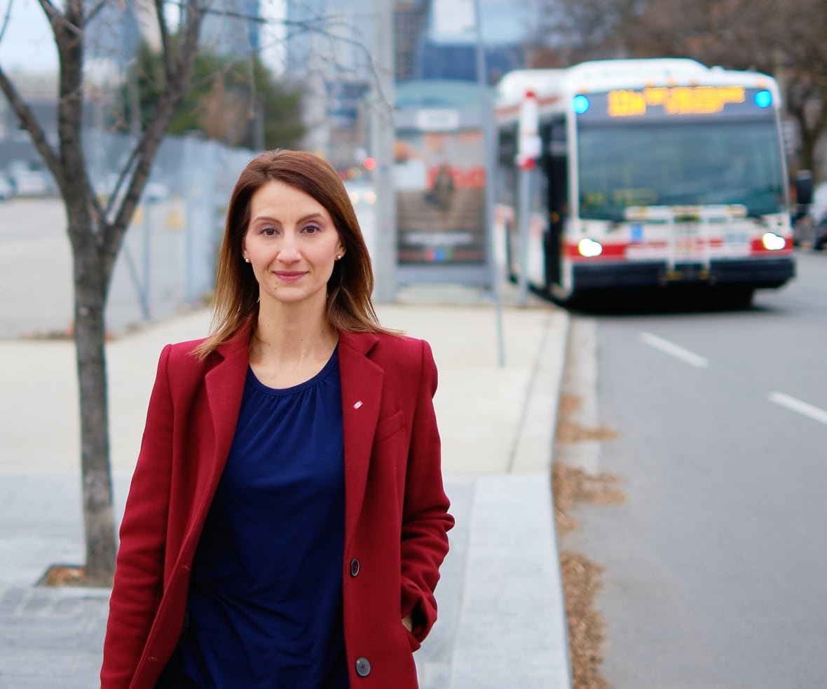 dr-josipa-petrunic Woman in red coat standing in front of a bus.