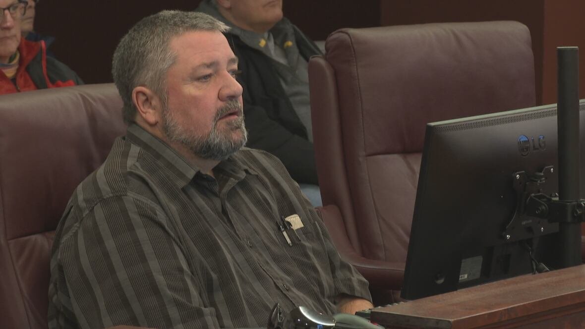 greg-gaudet-2025 A man wearing a dark short sleeved collored shirt sits in an office chair inside Summerside City Council chambers.