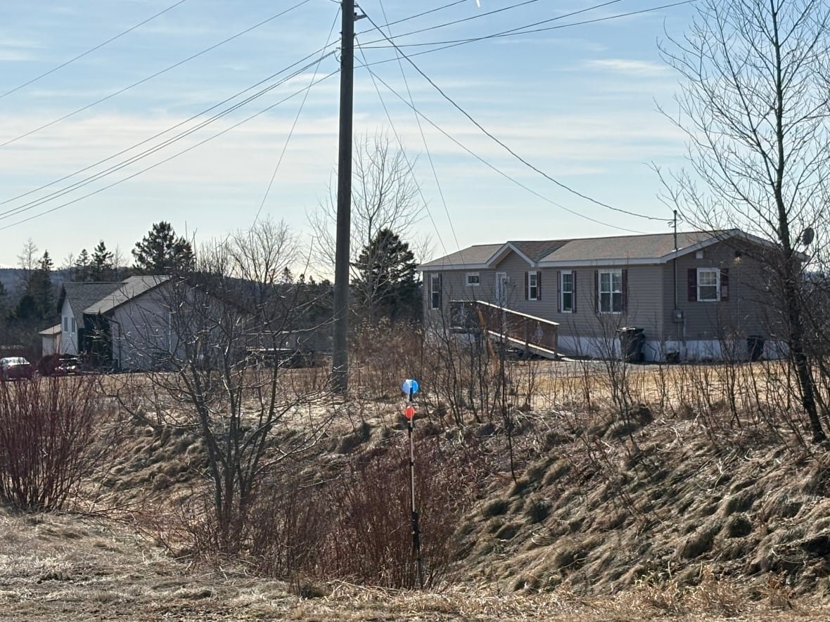 hampton-homes A distant photo of a medium-sized white house, left and a small, rectangular beige house, right.