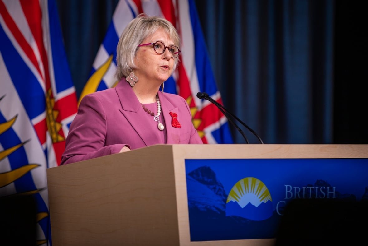 henry-avian-flu A woman in glasses and a pink outfit speaks from a podium that says 'British Columbia' on it.
