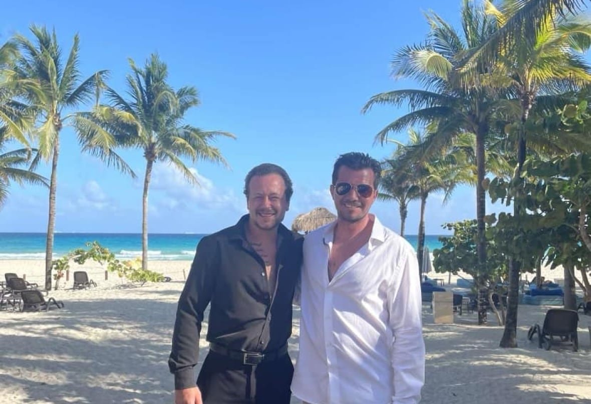 kyler-searle Two men on a beach with palm threes