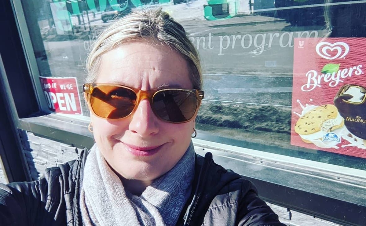 lisa-vezeau-allen A woman wearing sunglasses taking a selfie outside a restaurant.