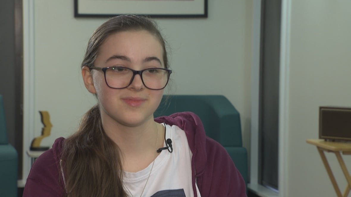 A girl with glasses wearing a purple sweater.