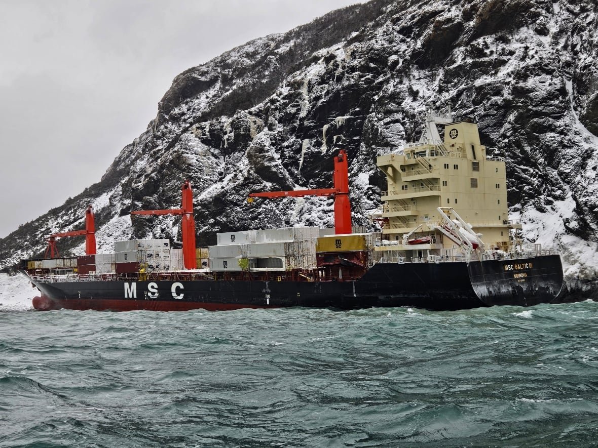 msc-baltic-iii-aground-1 A large cargo ship its on the water near a large cliff.